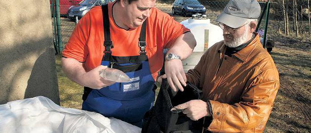 Vorrat für wenige Tage. Rainer Zingel (r.) hat sich wie viele andere Tremsdorfer am Wochenende mit Trinkwasserbeuteln eingedeckt. Das Wasser aus der Leitung schmeckt muffig. Wassermeister Andreas Roos (l.) hofft auf weitere Analyseergebnisse.