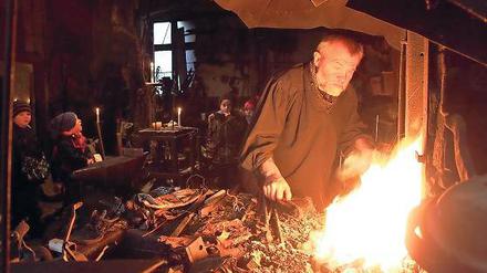 Staunen am Schmiedefeuer: Der Michendorfer Kunstschmied Michael Soika (vorne rechts) zeigte den Kindern der Potsdamer Kita „Friedenshaus“, wie man früher Schwerter herstellte. Bei den Kleinen dreht sich zurzeit alles um König Artus.
