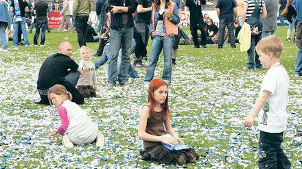 Her mit der Meisterschale. Babelsbergs Mannschaftskapitän Marian Unger stemmte die Trophäe am Samstag in die Höhe (oben), ehe Matthias Rudolph (l.) und Patrick Moritz (oben rechts) sowie Björn Laars mit Gattin Katrin und Sohn Bjarke (unten links) mit ihr posierten. Auch Erfolgscoach Dietmar Demuth (unten Mitte) - hier mit Fans beim Fotografieren genoss das Bad in der Menge, während das Meisterschafts-Konfetti zum begehrten Sammelobjekt mancher Zuschauer wurde (unten rechts).