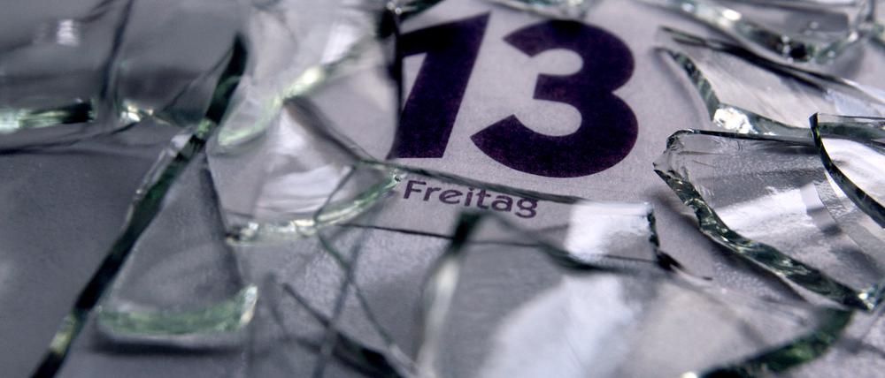 Ein Kalenderblatt mit dem Datum von Freitag dem 13. liegt unter Glasscherben. 
