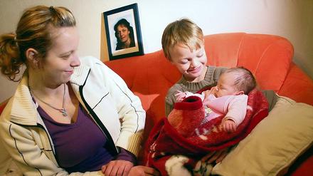 Junge Familie mit Sorgen. Die 20 Jahre alte Nadine Radon sitzt neben ihrem achtjährigen Bruder Florian Niemtschke, der ihr ein Monat altes Baby Zoe hält. Im Hintergrund: Das Bild der jüngst verstorbenen Mutter des Geschwisterpaars. Beide hoffen auf Spenden.