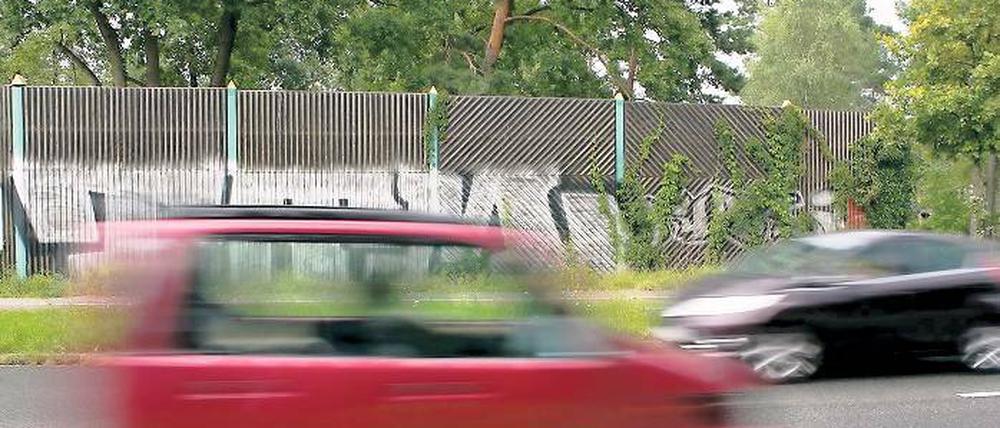 Aus Holz, aber vielleicht ohne Graffiti: So ähnlich wie hier am Stolper Weg soll auch die Lärmschutzwand am Stahnsdorfer Damm aussehen. Dort aber wird der rund vier Meter hohe Holzzaun fast über die gesamte Länge bis zur Schleuse von Bäumen verdeckt sein.
