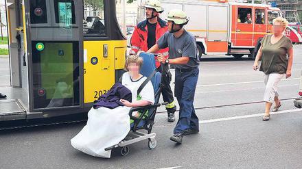 Schnelle Hilfe. Feuerwehrleute bringen eine Bewohnerin zur Tram.