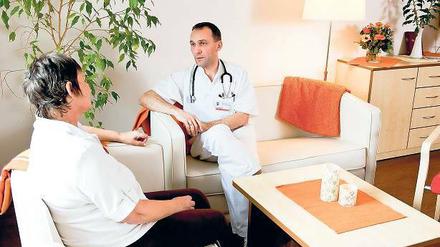 Im Wohnzimmer. Chefarzt Dr. Kämpfer mit einer Patientin.