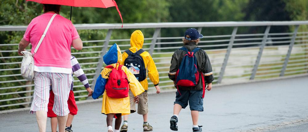 Eine Kindergartengruppe geht am Mittwoch in Potsdam während eines Regenschauers über eine Brücke...