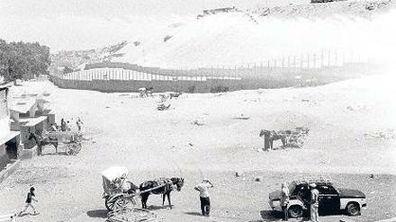 Unwirklich. Wie eine Filmkulisse wirkt diese wilde Bebauung im Sturm des Wüstenwindes am Rande der eingemauerten Pyramiden.