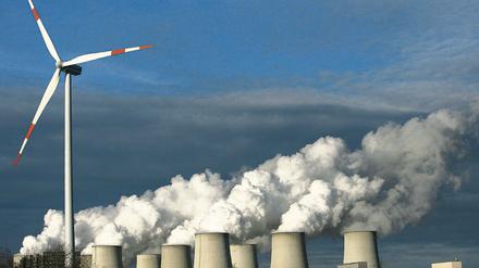 Zweierlei Energie. Ein Windrad dreht sich vor den Kühltürmen eines Kohlekraftwerkes im brandenburgischen Jänschwalde.