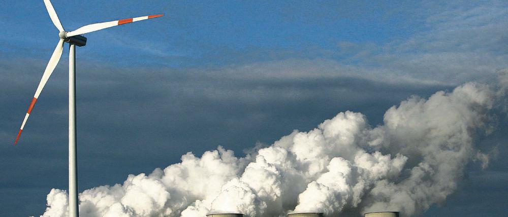Zweierlei Energie. Ein Windrad dreht sich vor den Kühltürmen eines Kohlekraftwerkes im brandenburgischen Jänschwalde.