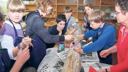 Fantasie gefragt. Kinder der 5. Klassen bearbeiten einen Baumstamm.