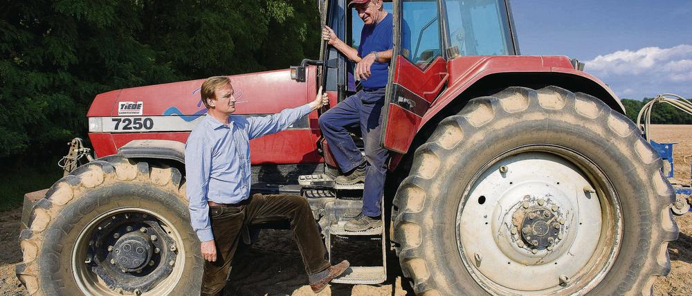 Der Landwirt Hans-Georg von der Marwitz (l) unterhält sich mit seinem Angestellten Joachim Bleschke am Traktor. Der Enkel des letzten Gutsbesitzers betreibt Landwirtschaft im Dorf seiner Ahnen.