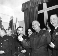General Dwight D. Eisenhower hält die zwei Stifte, mit denen die bedingungslose Kapitulation der Wehrmacht am 7. Mai in Reims unterzeichnet wurde, in Anlehnung an das Victory-Zeichen wie ein «V».