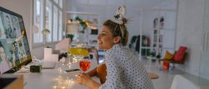 Photo of a young woman celebrating Christmas by having a virtual Christmas party with her friends; drinking wine, celebrating Christmas and holidays apart from friends and family, and practicing social distancing.