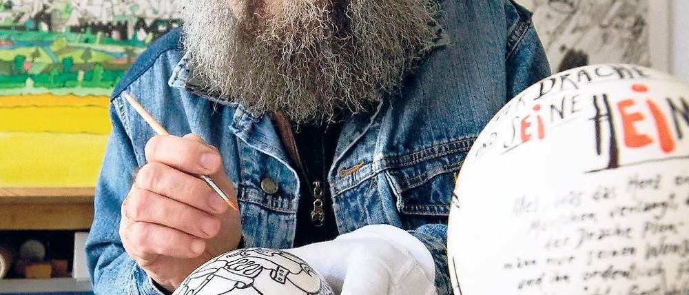 Designer Meinhard Bärmich malt in seinem Atelier die Figur eines Wassermanns auf einem Straußenei aus.