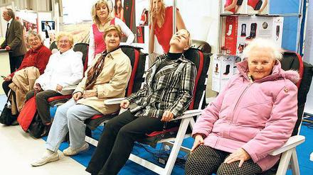 Messebesucherinnen versuchen in Relaxsesseln zu entspannen.