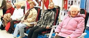 Messebesucherinnen versuchen in Relaxsesseln zu entspannen.