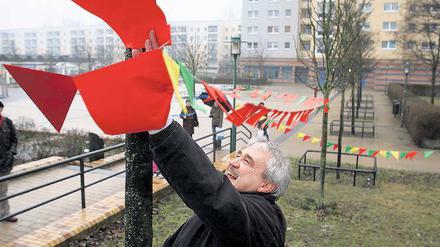 Im Wind. Gerrit Friedrich von der AG Senioren befestigt eine Wimpelkette, die die rund 450 Unterschriften von Anwohnern zur positiven Gestaltung des Wohngebietes symbolisieren soll.