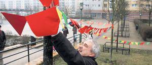 Im Wind. Gerrit Friedrich von der AG Senioren befestigt eine Wimpelkette, die die rund 450 Unterschriften von Anwohnern zur positiven Gestaltung des Wohngebietes symbolisieren soll.