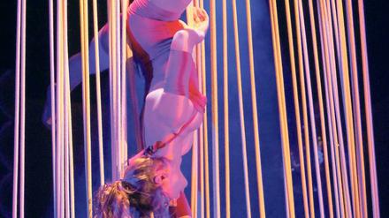 Spagat an Spaghetti. Die französische Artistin Charlotte de la Bretèque turnt an einer Art Vorhang aus Seilen.
