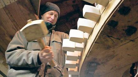 Zahn-Arbeiten. Zimmerer Ulrich Blümner bearbeitet die als Kämme bezeichneten Zähne des Mahlwerks der Historischen Mühle von Sanssouci.