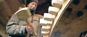 Zahn-Arbeiten. Zimmerer Ulrich Blümner bearbeitet die als Kämme bezeichneten Zähne des Mahlwerks der Historischen Mühle von Sanssouci.