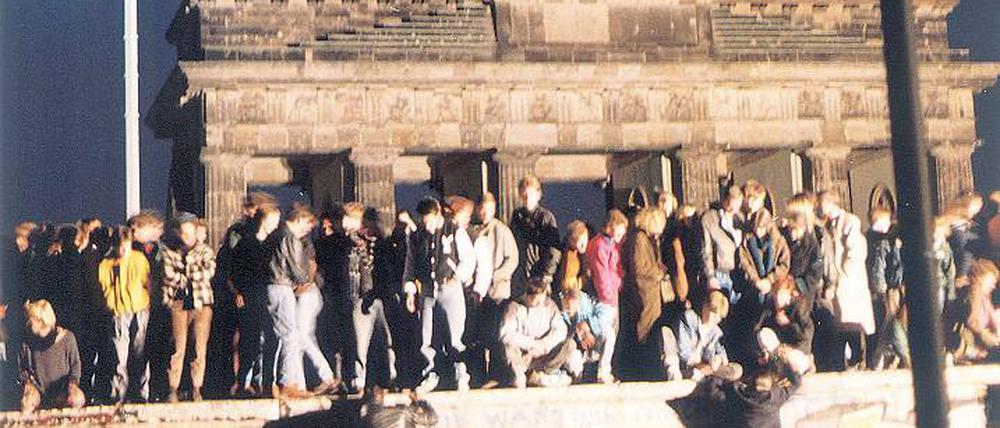 Bild voller Symbolkraft. Feiernde Menschen auf der Berliner Mauer vor dem Brandenburger Tor am 9. November 1989.