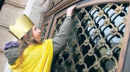 Mit Umhang und Krone. Clara aus Werder befestigte gestern den Segensspruch über dem Eingang des Stadthauses. Noch bis Ende Januar sind Sternsinger in der Landeshauptstadt unterwegs. Doch nicht immer wird der christliche Neujahrsbrauch respektiert.