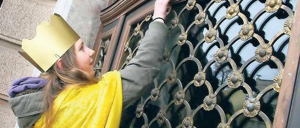 Mit Umhang und Krone. Clara aus Werder befestigte gestern den Segensspruch über dem Eingang des Stadthauses. Noch bis Ende Januar sind Sternsinger in der Landeshauptstadt unterwegs. Doch nicht immer wird der christliche Neujahrsbrauch respektiert.