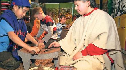 Mit dem Nudelholz: Kinder beim Zermahlen von Kakao-Bohnen.