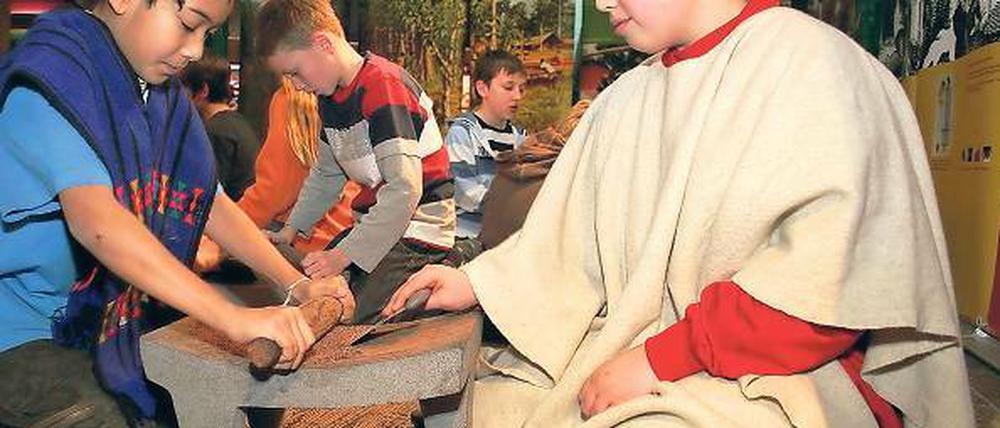 Mit dem Nudelholz: Kinder beim Zermahlen von Kakao-Bohnen.
