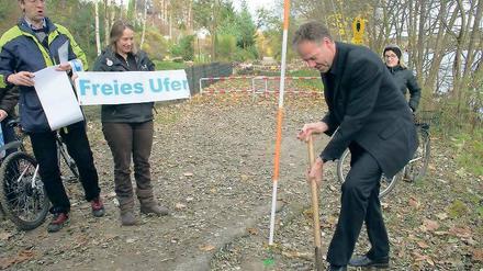 Symbolhaft: Baudezernent Matthias Klipp gestern beim Spatenstich für ein befestigtes Uferwegestück am Groß Glienicker See. Im Hintergrund ein gesperrtes Wegestück.
