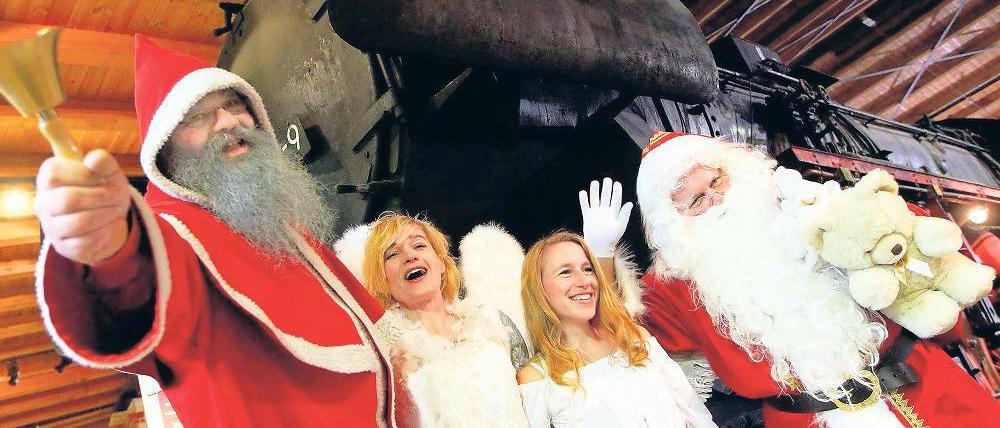 Teamarbeit. Weihnachtsmänner posieren gemeinsam mit Engeln.