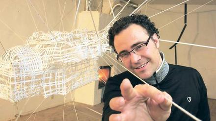 In seinem Potsdamer Gastatelier hat Gianin Conrad eine große Rauminstallation aus Fäden geknüpft. In der Mitte hängt, wie die Spinne im Netz, eine rücklings schwebende Figur.