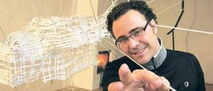 In seinem Potsdamer Gastatelier hat Gianin Conrad eine große Rauminstallation aus Fäden geknüpft. In der Mitte hängt, wie die Spinne im Netz, eine rücklings schwebende Figur.