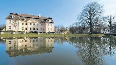 Schloss Branitz spiegelt sich im Schlossteich auf dem Gelände vom Fürst-Pückler-Museum Park & Schloss Branitz bei Cottbus.