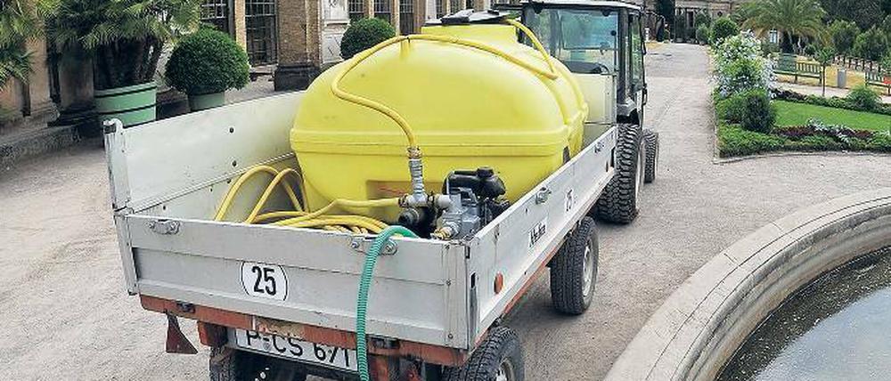 Ein Gärtner befüllt vor der Orangerie einen 1000 Liter Wassertank.