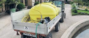 Ein Gärtner befüllt vor der Orangerie einen 1000 Liter Wassertank.