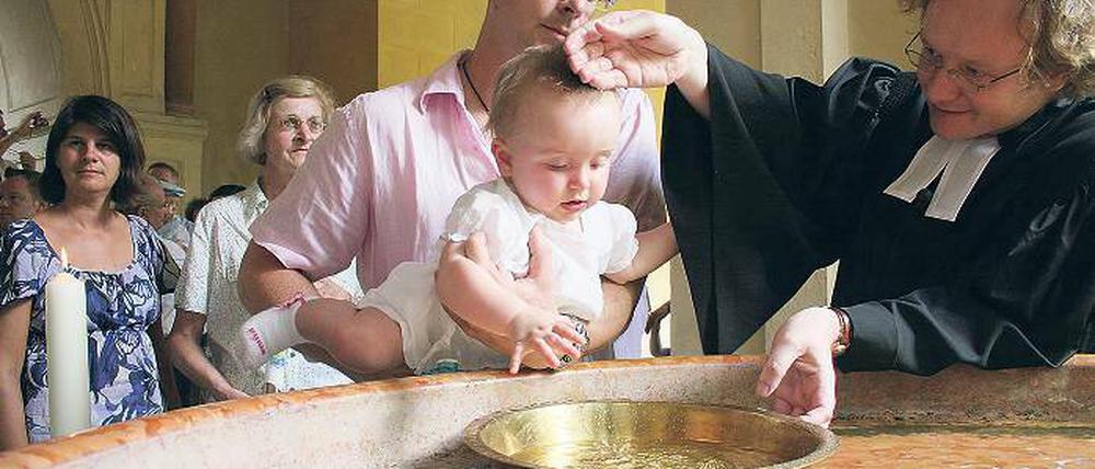 Pfarrer Matthias Mieke tauft die kleine Emily am Springbrunnen vor der Friedenskirche. Vier Orte waren auserkoren worden, um die erste Potsdamer Gemeinschaftstaufe zu zelebrieren. Danach wurde gemeinsam im Atrium der Kirche gefeiert.