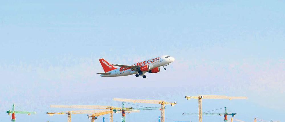 Symbol gemeinsamer Wirtschaftspolitik: Ein Passagierflugzeug überfliegt am Flughafen Berlin-Brandenburg International (BBI) in Schönefeld beim Start Baukräne. Am 7. Mai wird Richtfest für den Airport gefeiert.