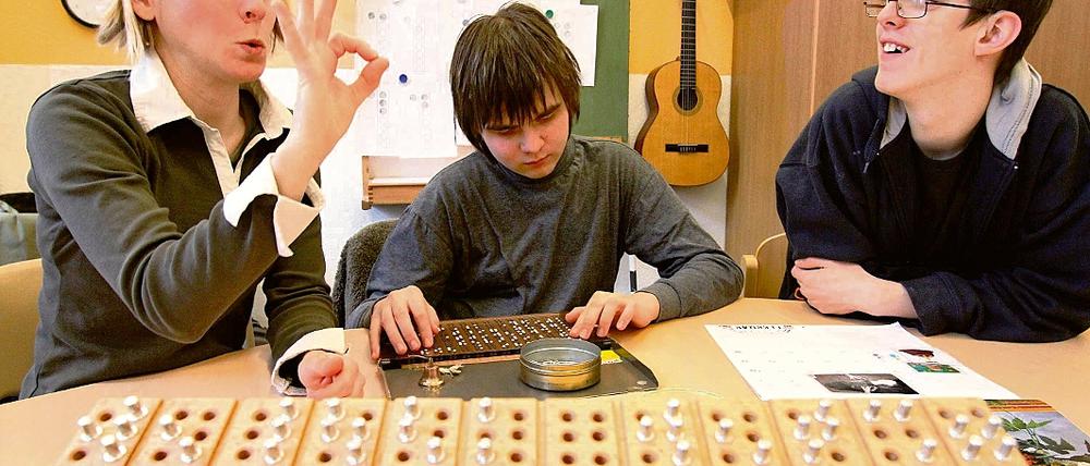 Kommunikativer Fingerzeig. Miriam Winter (l.) ist eine von 25 Sonderpädagoginnen an der Babelsberger Oberlinschule. Die Kommunikation zwischen Schülern und Lehrer geschieht oft mittels der Gebärdensprache, hier spricht Winter zu den hörsehbehinderten Schülern Gerard und Edi (M.).