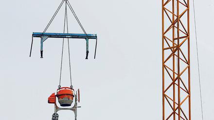 Unerreichbar für Langfinger. Eine Arbeitsbank und eine Betonmischmaschine hängen an einem Kran auf einer Baustelle. Einige Maßnahmen zum Schutz vor Klau am Bau kosten kein Geld und sind trotzdem effektiv.