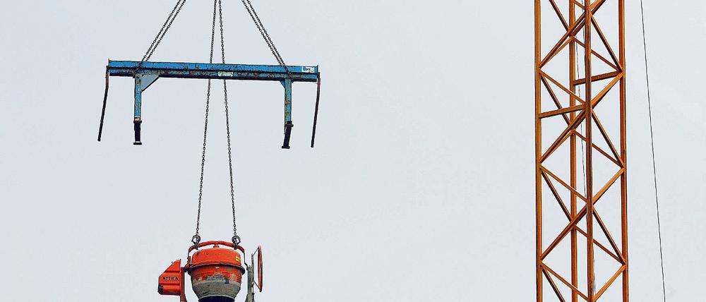 Unerreichbar für Langfinger. Eine Arbeitsbank und eine Betonmischmaschine hängen an einem Kran auf einer Baustelle. Einige Maßnahmen zum Schutz vor Klau am Bau kosten kein Geld und sind trotzdem effektiv.