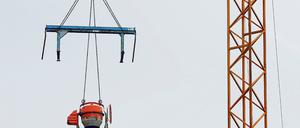 Unerreichbar für Langfinger. Eine Arbeitsbank und eine Betonmischmaschine hängen an einem Kran auf einer Baustelle. Einige Maßnahmen zum Schutz vor Klau am Bau kosten kein Geld und sind trotzdem effektiv.