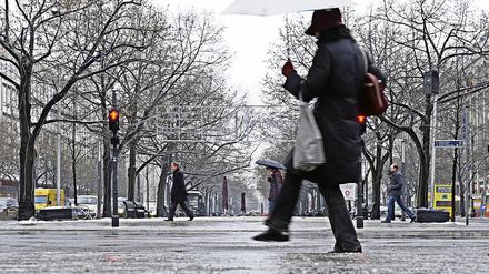 Rutschgefahr. Mit vorsichtigen Schritten überquerte eine Fußgängerin am Dienstag eine spiegelglatte Straße in Berlin, nachdem Regen die Fahrbahn mit einer Eisschicht überzogen hatte.