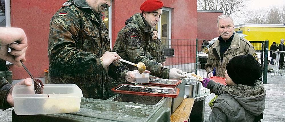 Weihnachten am Schlaatz: Die Bundeswehr kochte am Bürgerhaus Rindergulasch für mehr als 100 Menschen (Bild li.), im Asylbewerberheim (Bild r.) überreichten Jann Jakobs (l.), Maria von Pawelsz-Wolf und Aldriane Franke Thiemann (hinten) Geschenke.