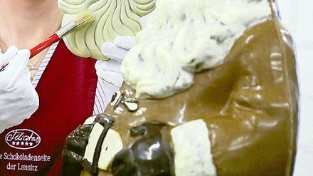 Eine Mitarbeiterin der Confiserie Felicitas bearbeitet Schokoladen-Weihnachtsmänner.