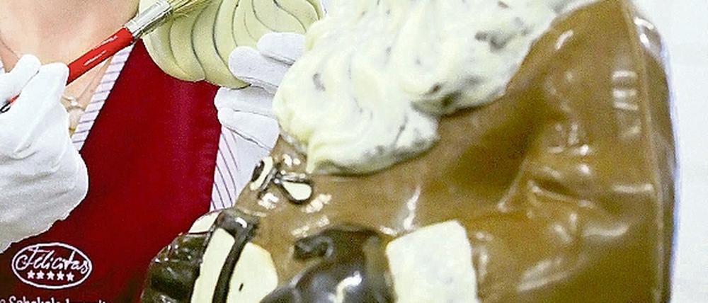 Eine Mitarbeiterin der Confiserie Felicitas bearbeitet Schokoladen-Weihnachtsmänner.