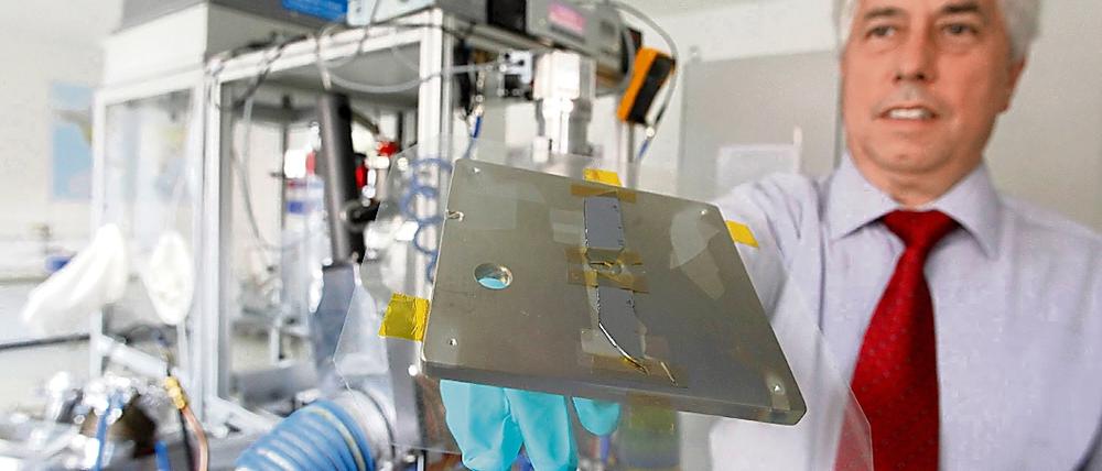 Peter Siemroth zeigt einen Träger mit der Nanokohlenstoffbeschichtung.