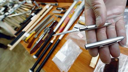 Heimtückische Waffe: Ein Polizist zeigt eine in einem Kugelschreiber versteckte Stichwaffe, die bei einer Razzia entdeckt wurde.