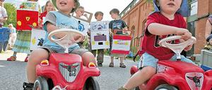 Papp-Autos brauchen keine Stellfläche. Familien protestieren mit ihren Kindern gegen die weitere Bebauung.