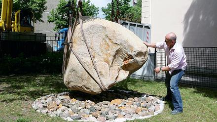 7,5 Tonnen Granit werden als Findling in den Hof des Naturkundemuseums eingeschwebt. Der Geschäftsführer der Bauzuschlagstoffe und Recycling GmbH, Götz Eckert, will ihn in die passende Kuhle dirigieren.